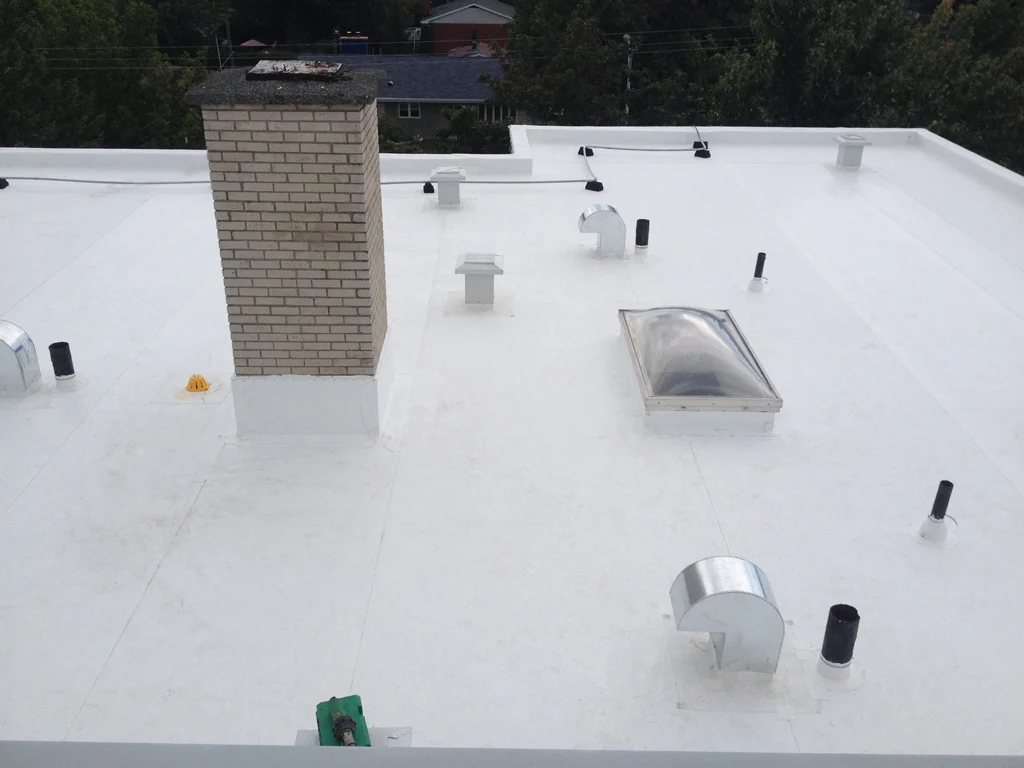 New white flat roof with chimney, vents, and skylight